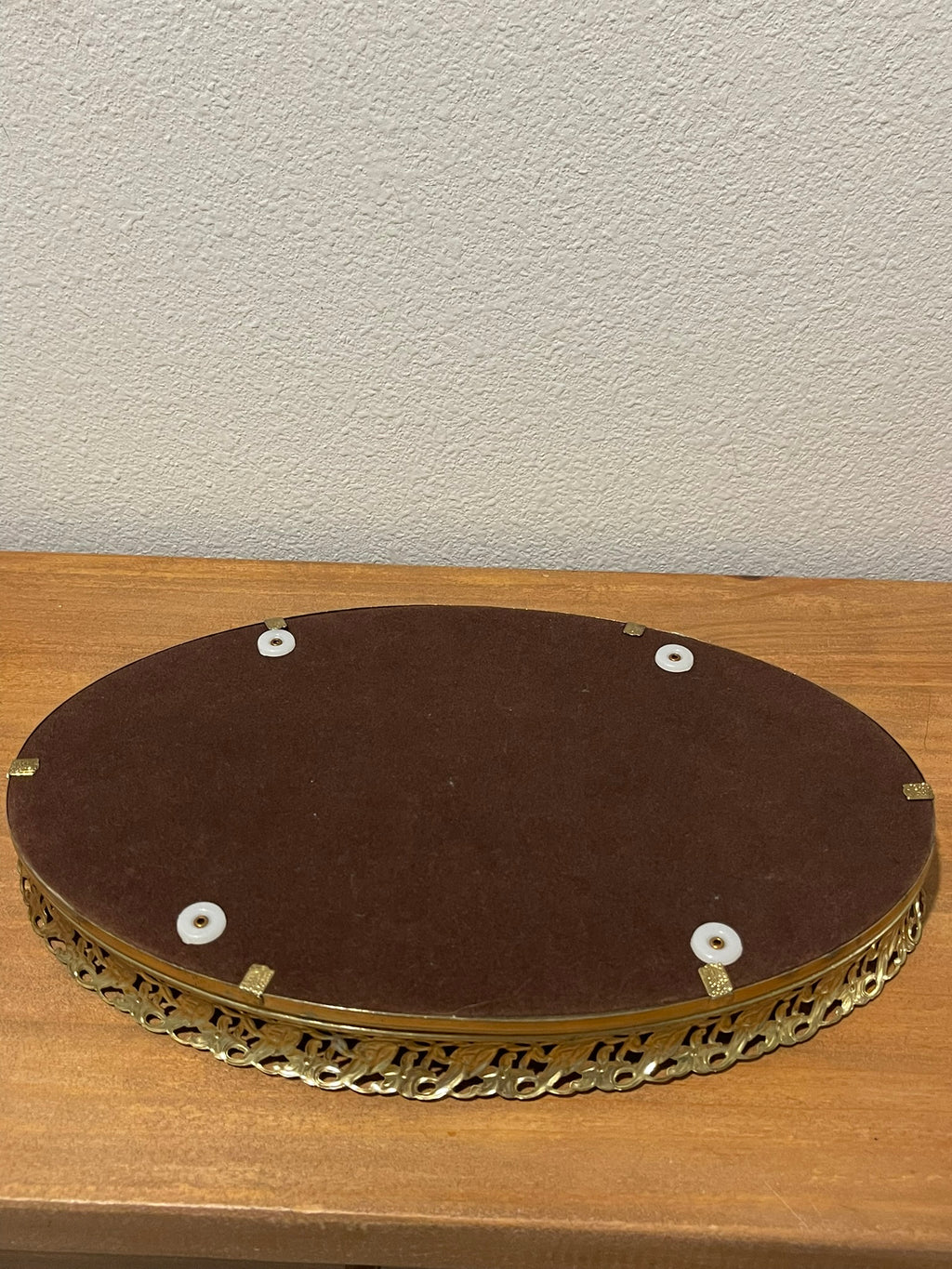 Underside of vintage gold filigree vanity tray showing velvet lining and rubber feet