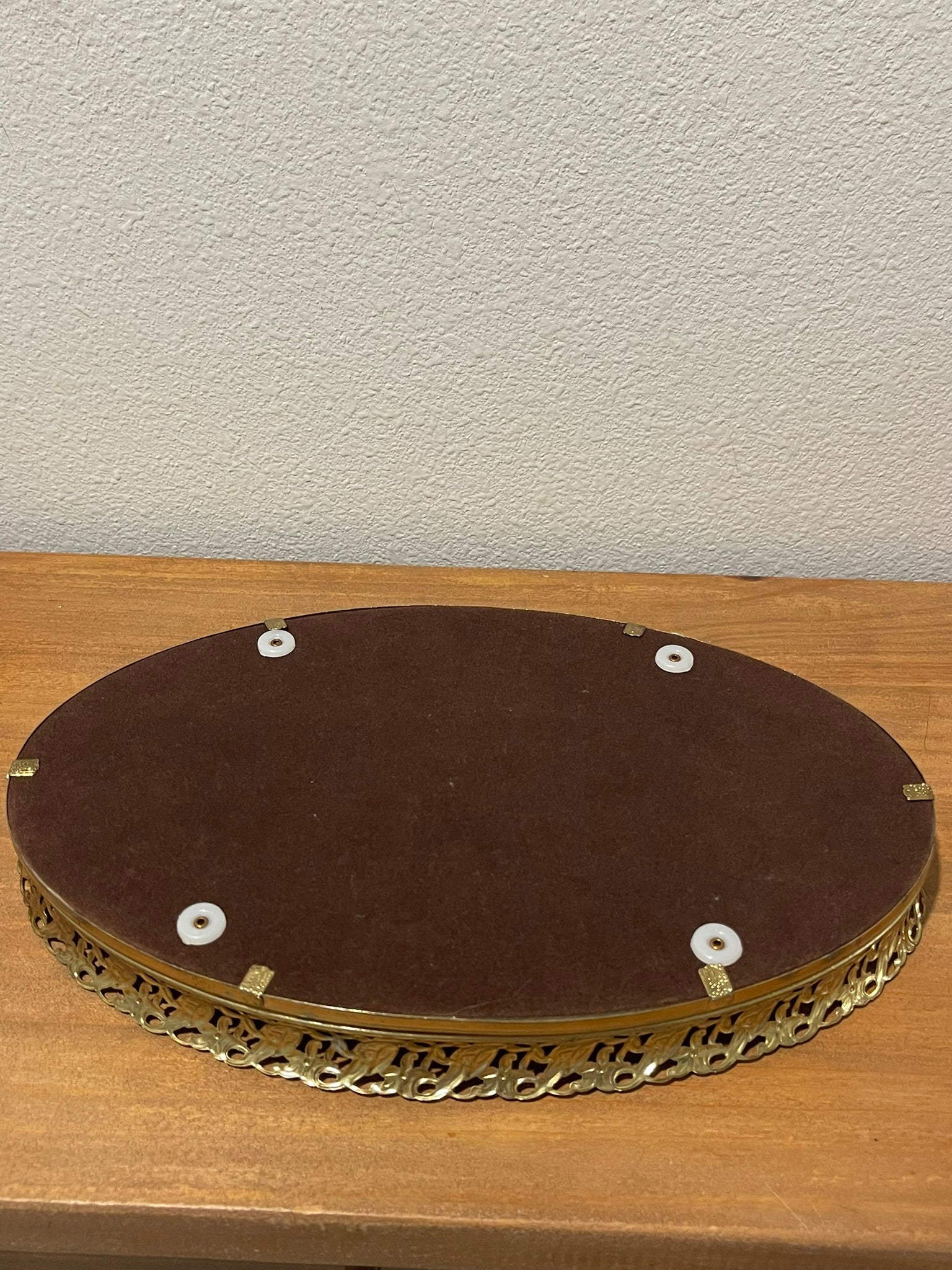 Underside of vintage gold filigree vanity tray showing velvet lining and rubber feet