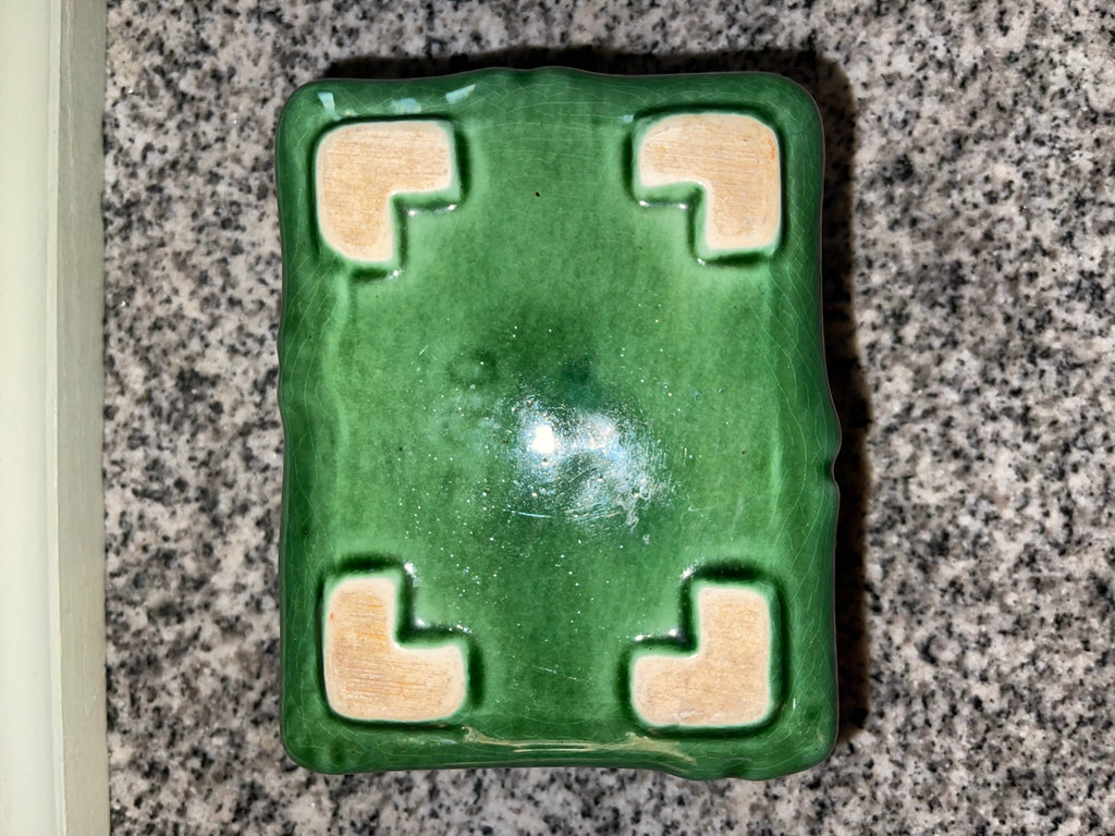 Bottom of vintage green bamboo planter showing unglazed corner feet