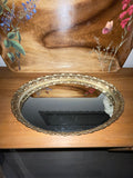 Vintage gold filigree oval mirror vanity tray, top view on dresser with botanical tray behind